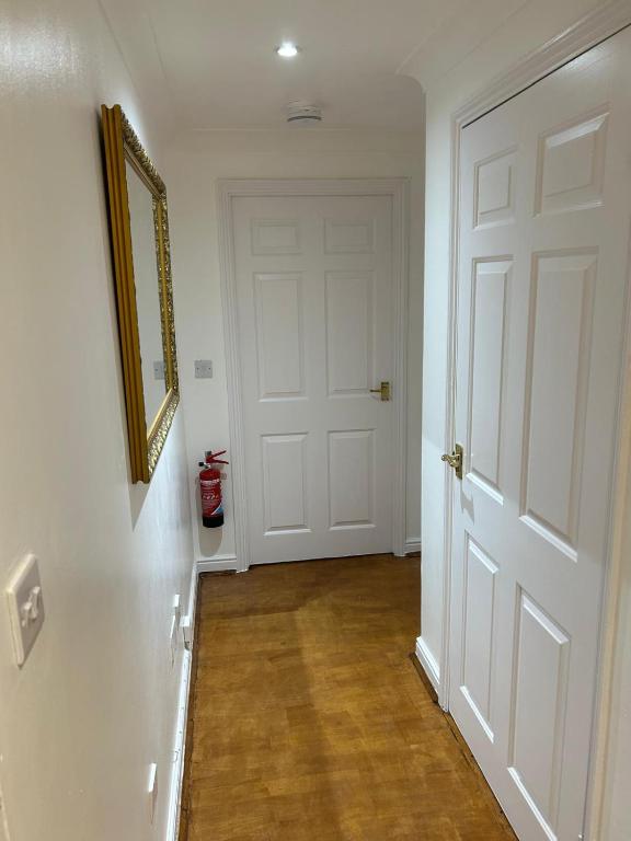 a hallway with a white door and a wooden floor at StaxBnB in London