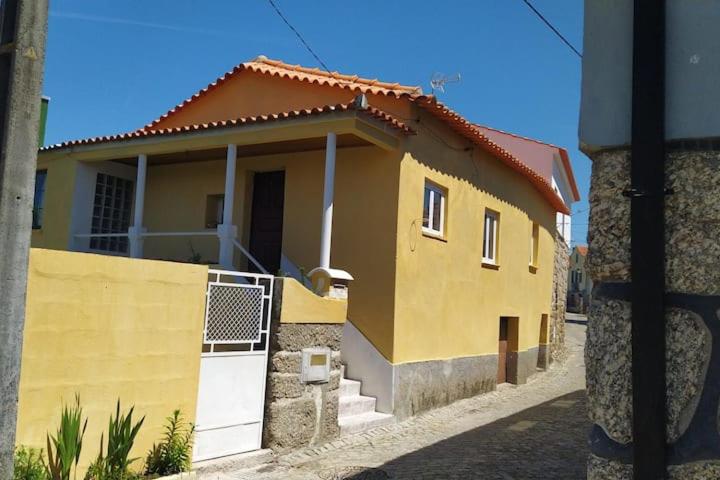 a yellow house with a white door on a street at Casa Isabel in Póvoa dos Mosqueiros