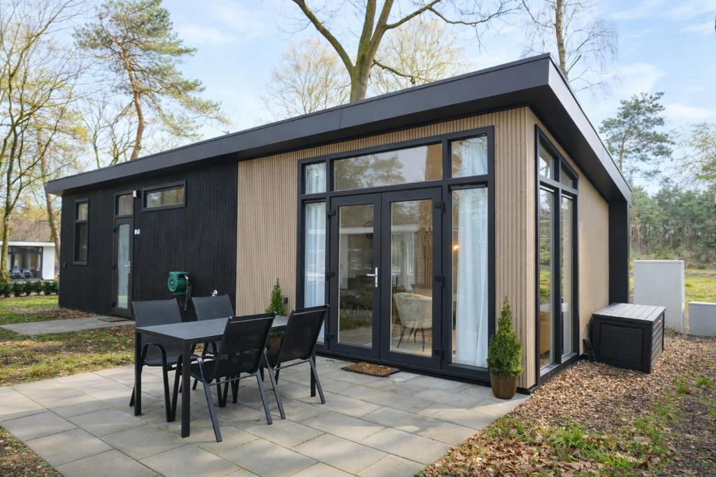 a black tiny house with a table and chairs at Colibri Huisje in Haarle