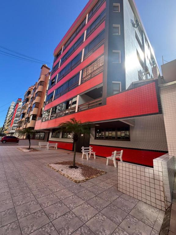 a tall building with benches in front of it at Apartamento em Capão da Canoa com Ar-condicionado in Capão da Canoa