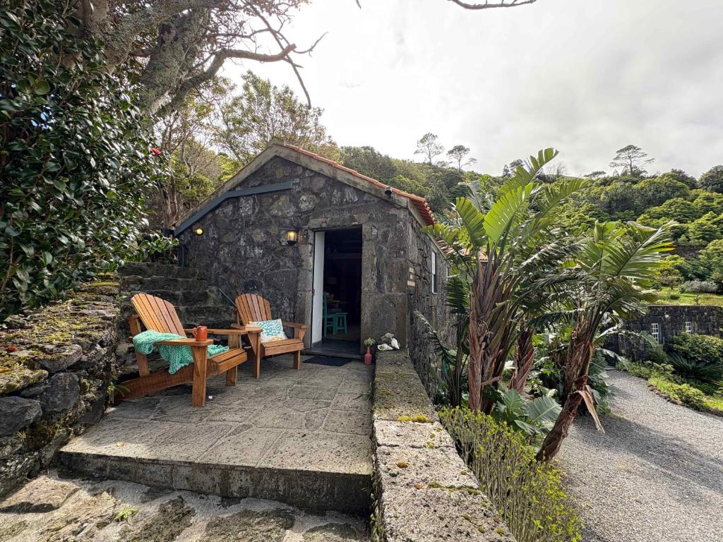 a small stone shed with two chairs and a table at Casa do Laureano in Santo Amaro