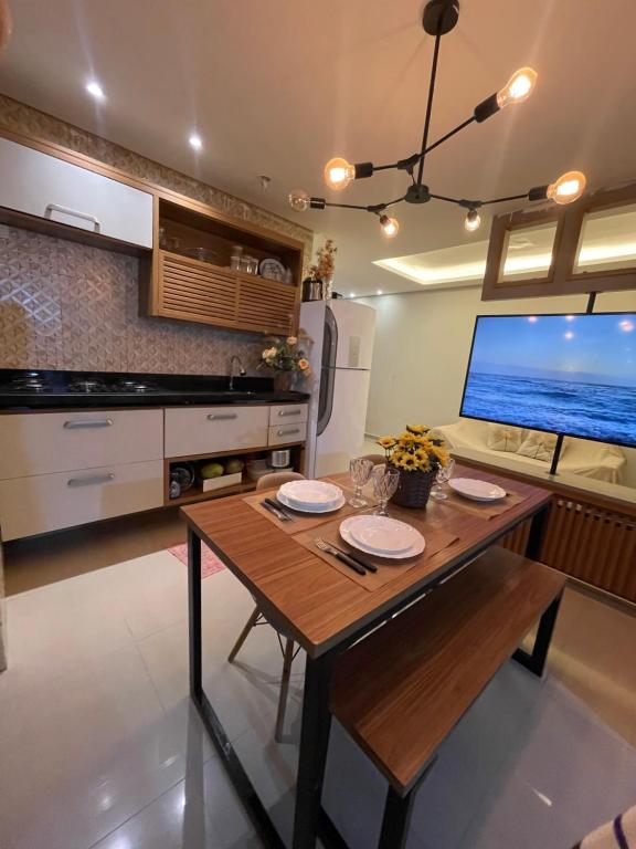 a kitchen with a wooden table and a large tv at Casa Lima Premium in Arapiraca