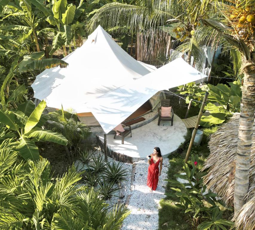 a woman standing in front of a white tent at Nómada Tayrona - Riverside Suites in Los Naranjos
