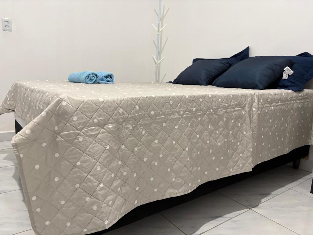a bed with a white comforter and blue pillows at Studio suite casal in Teresina