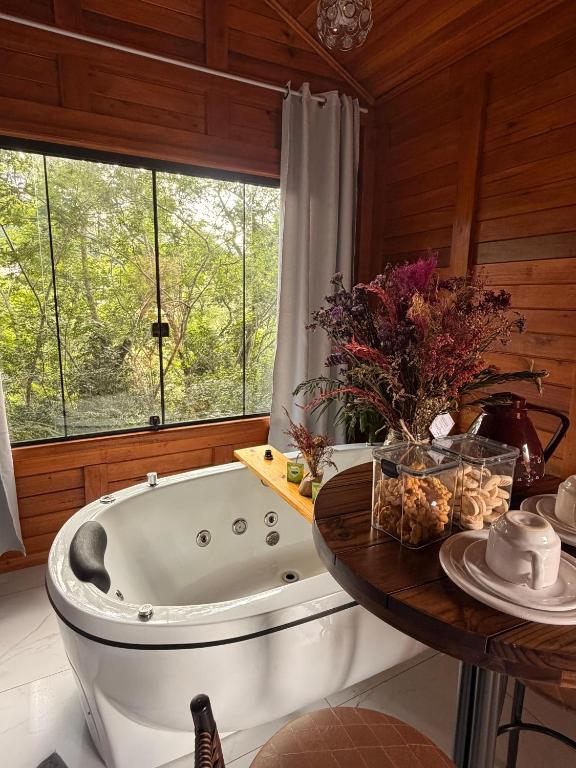 a bathroom with a tub and a table with flowers at Cabana Zanetti in Santa Teresa