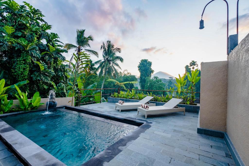 a swimming pool with two lounge chairs and a swimming pool at Taru Sebatu Villa in Ubud