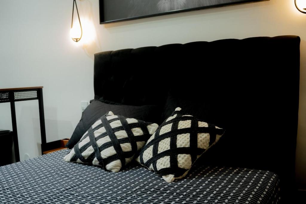 a bed with two black and white pillows on it at Studio confort com ar Centro de Niteroi in Niterói