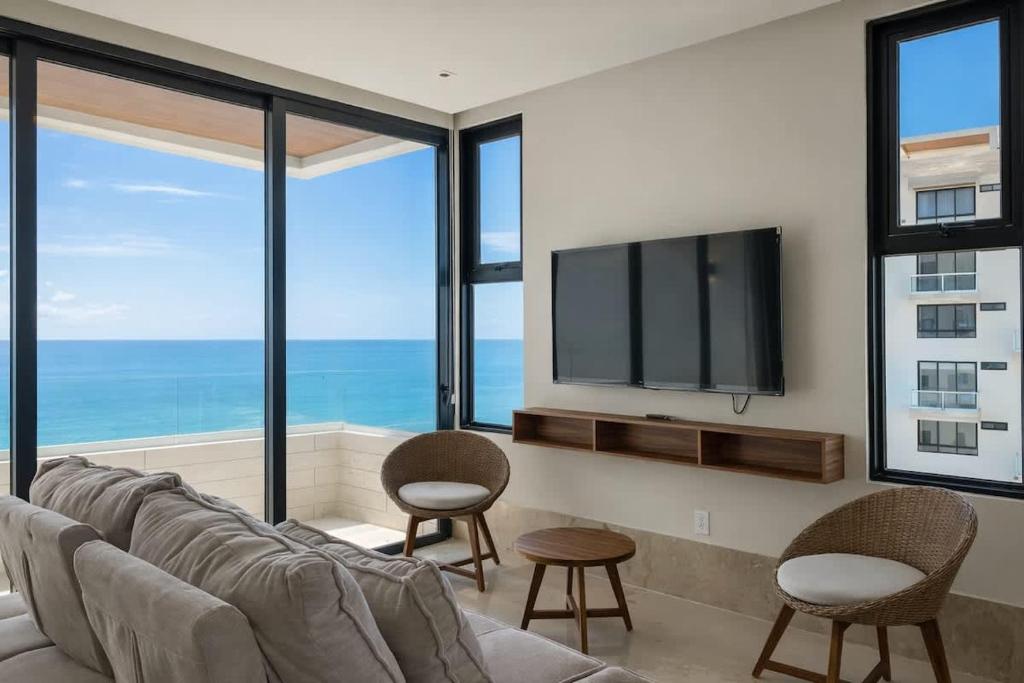 a living room with a couch and chairs and a tv at Distrito Puerto by Andiani Travel in Puerto Morelos