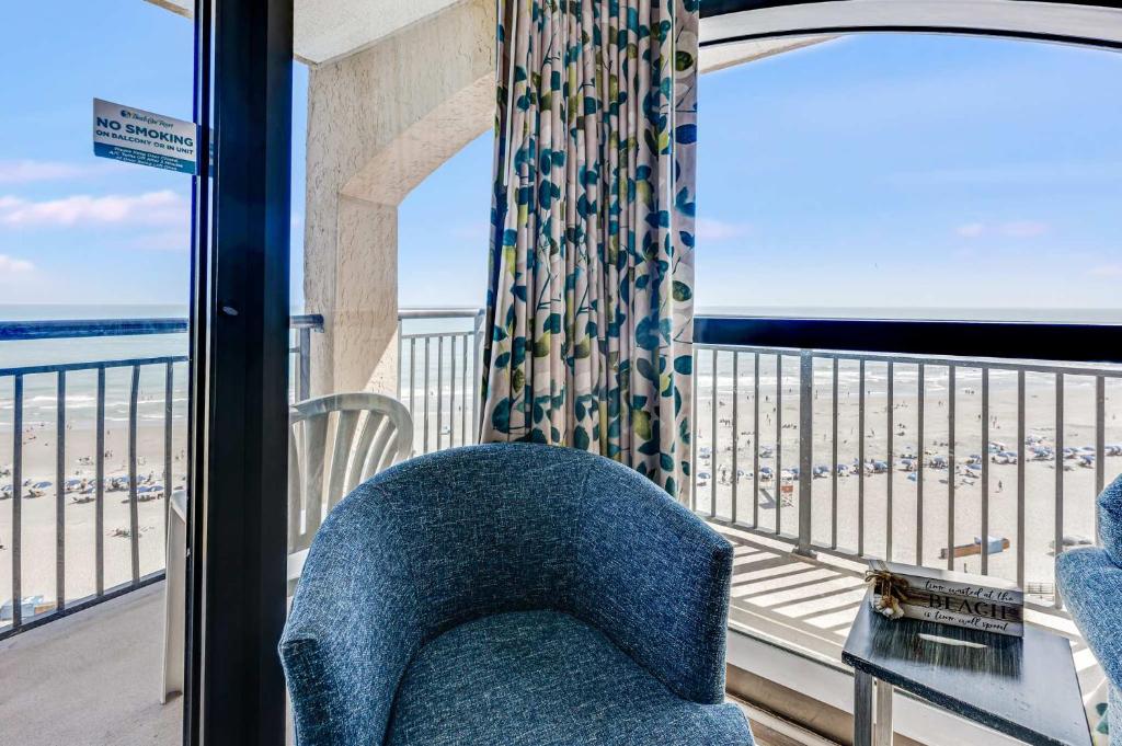 a blue chair on a balcony with a view of the beach at Beautifully Decorated Condo with Amzing Ocean View in Myrtle Beach