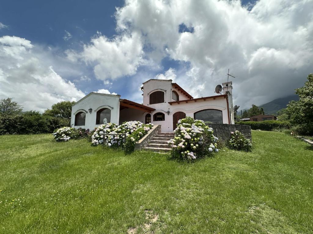a church on a hill with flowers in the grass at Casa Tafi del Valle in Tafí del Valle