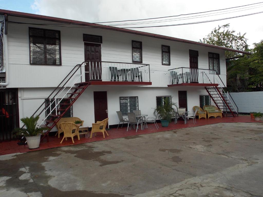 uma casa branca com escadas, mesas e cadeiras em At Rachel em Paramaribo
