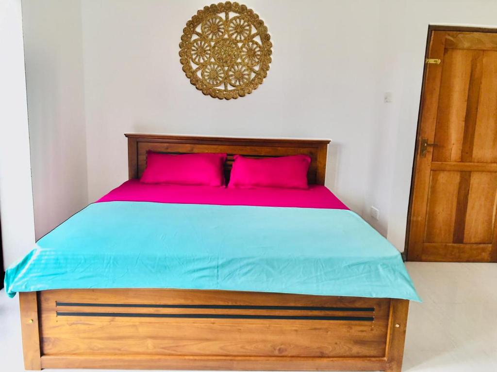 a bedroom with a bed with pink and blue sheets at The weligama in Weligama