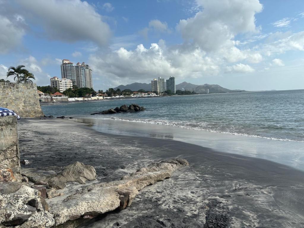a beach with buildings in the background and the ocean at Beach House in Coronado in Nueva Gorgona