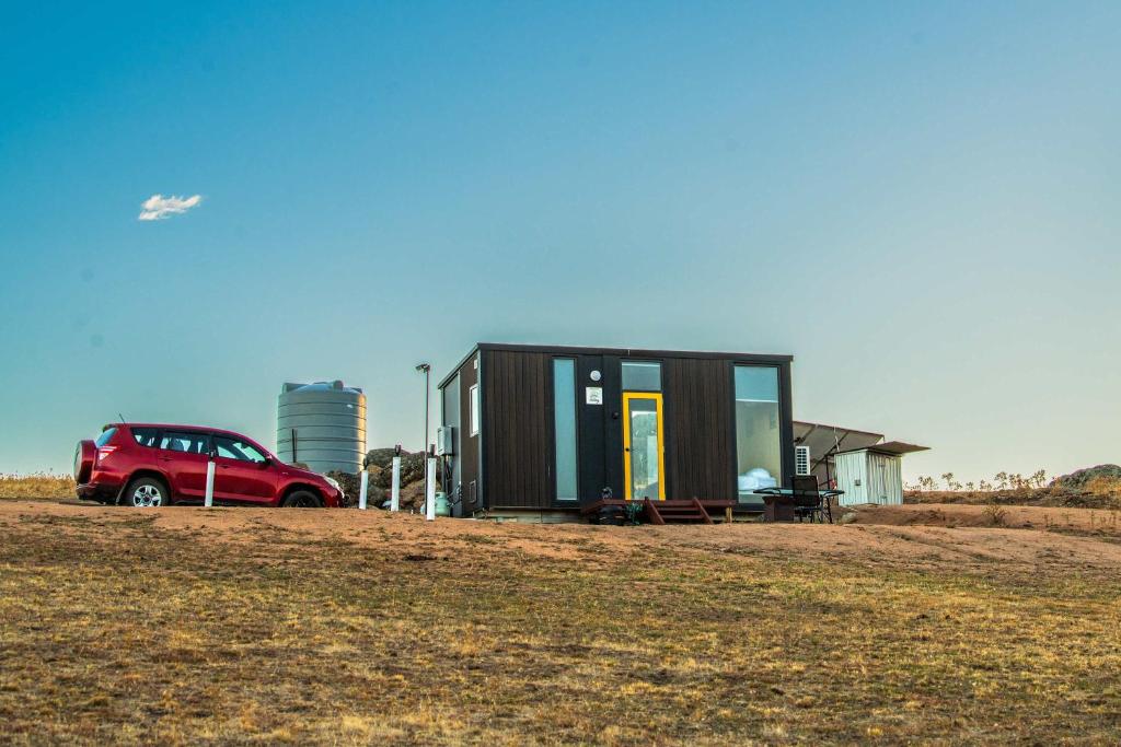 a small house with a car parked in a field at Gunyah by Tiny Away in Mount McDonald