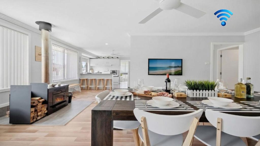 a dining room and living room with a table and chairs at Alka Beach House in Callala Beach