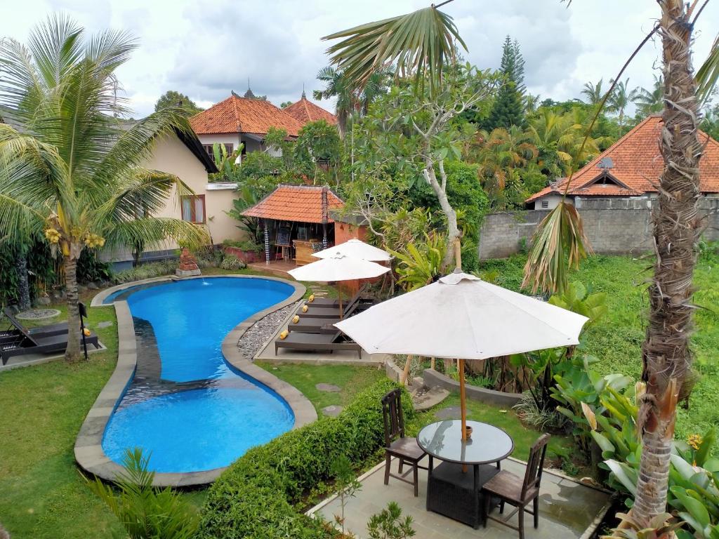 an image of a resort pool with tables and umbrellas at Pondok Massas Ubud in Ubud