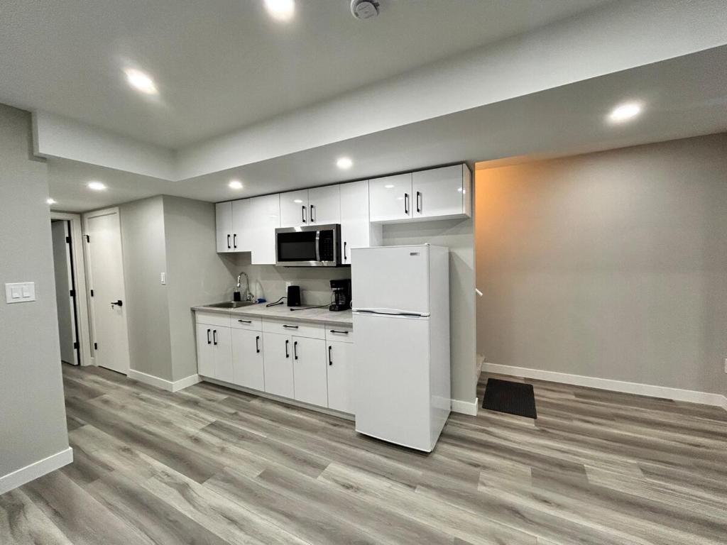 a kitchen with white cabinets and a white refrigerator at Spacious and Stylish Private Basement Suite - 1 bed and 1 rec room in Winnipeg
