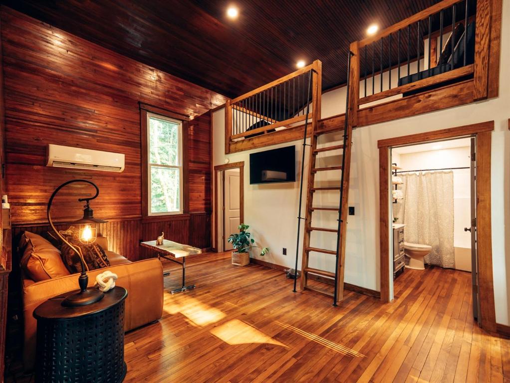 a living room with a loft bed and wooden walls at Corton Lodge Bell Tower Suite Private Riverfront in Clendenin