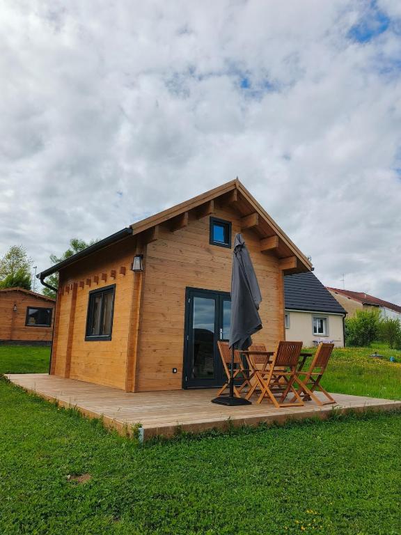 a log cabin with two chairs and an umbrella at Charmant petit chalet jurassien in Saint-Lamain