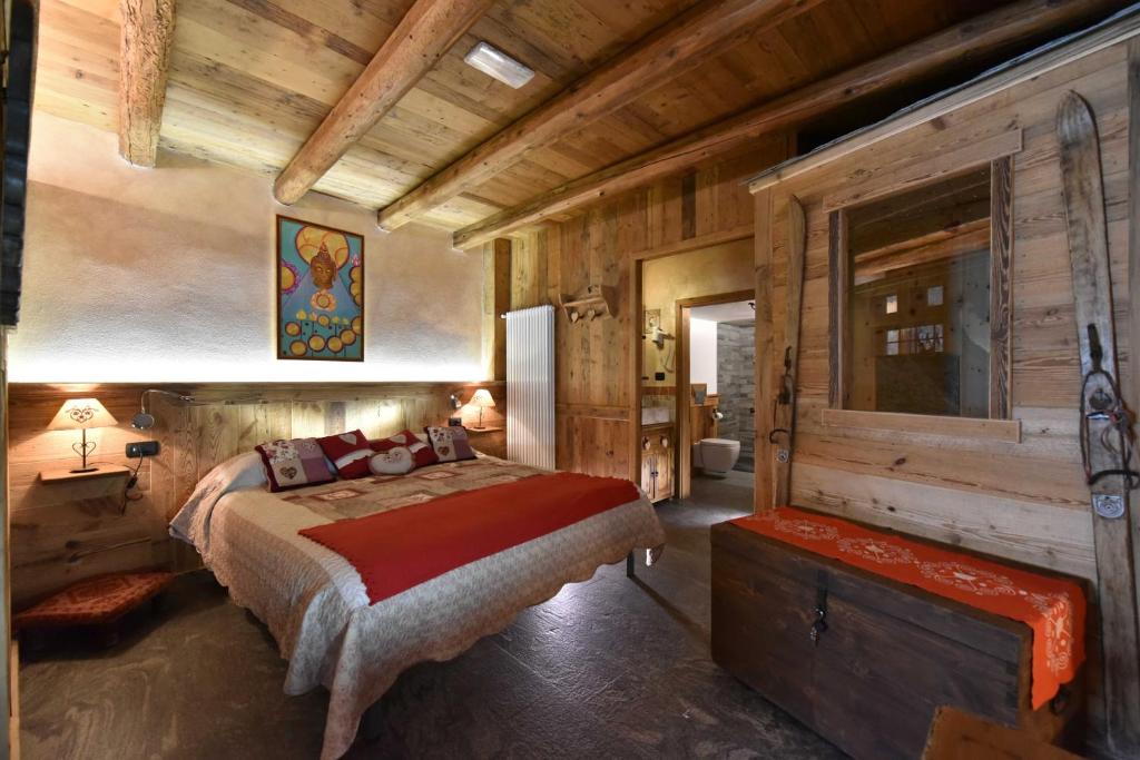 ein Schlafzimmer mit einem Bett und einer Holzwand in der Unterkunft L'Ancien Paquier Chambre D'Hotes in Valtournenche