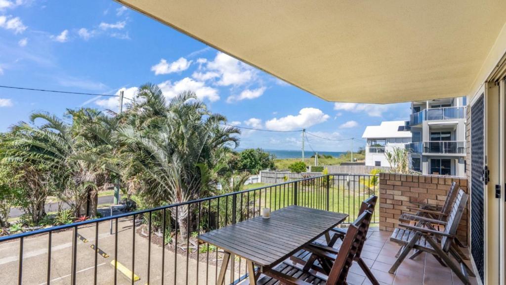 a balcony with a wooden table and two chairs at The Calm At Moreton View in Woorim