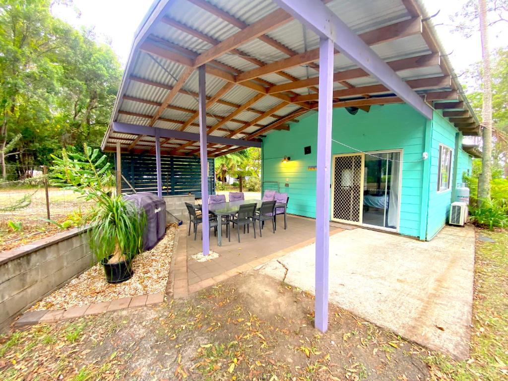 a blue house with a table and chairs on a patio at Lakeside 3-BR Forest Cottage in Laurieton