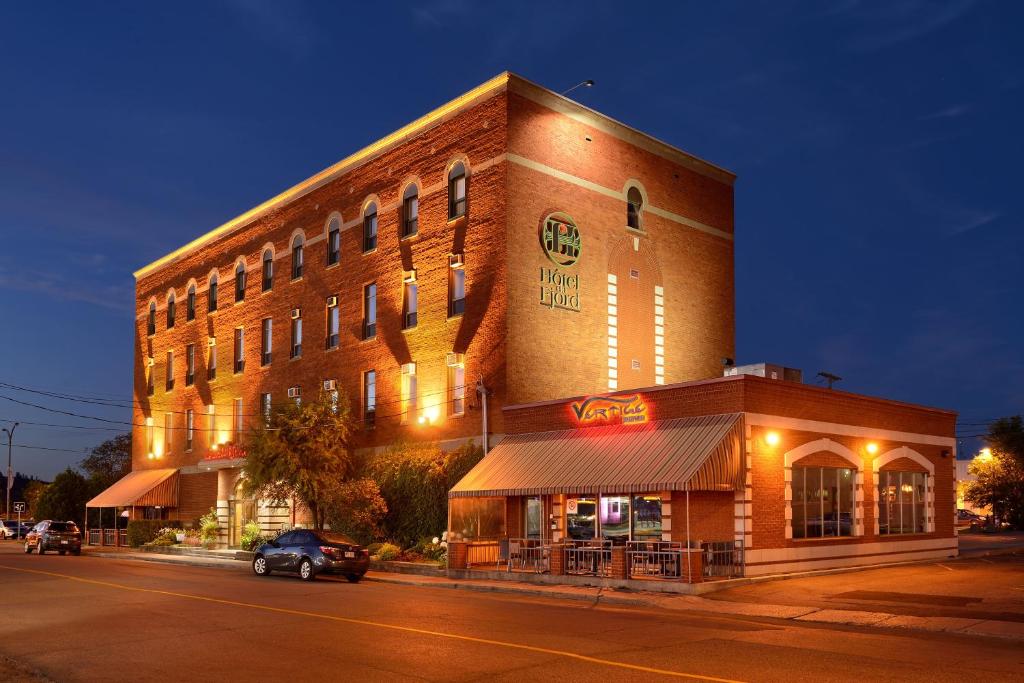 - un grand bâtiment en briques dans une rue la nuit dans l'établissement Hotel du Fjord, à Saguenay