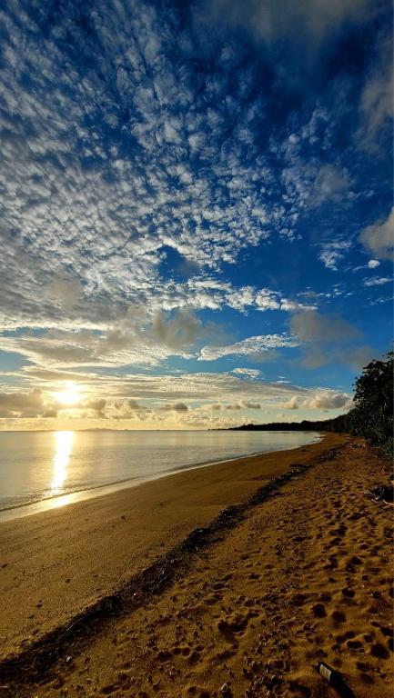 a sandy beach with the sun reflecting on the water at sandbar Homestay in Lautoka