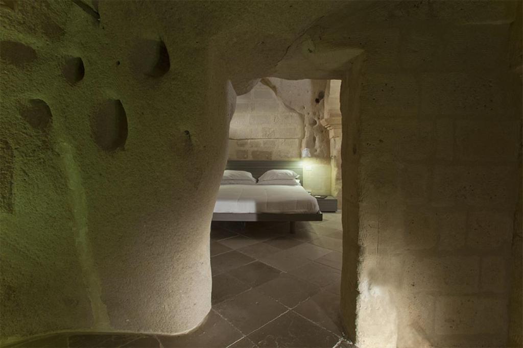 
a room with a wall of stone and a stairway at Antico Convicino Rooms Suites & SPA in Matera
