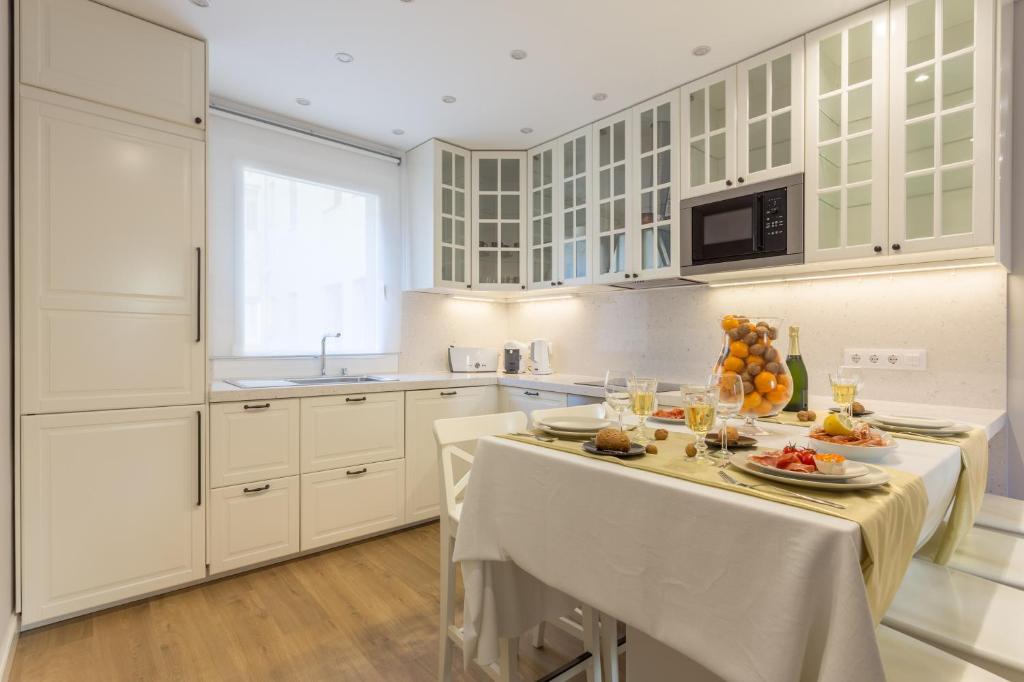 a kitchen with white cabinets and a table with food on it at Moreryadom in Barcelona