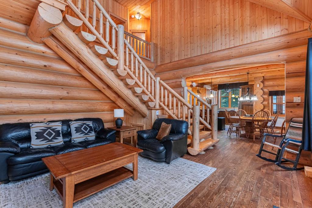 a living room with a staircase in a log cabin at Fiddler Lake Resort - Bear 22 in Mille-Isles