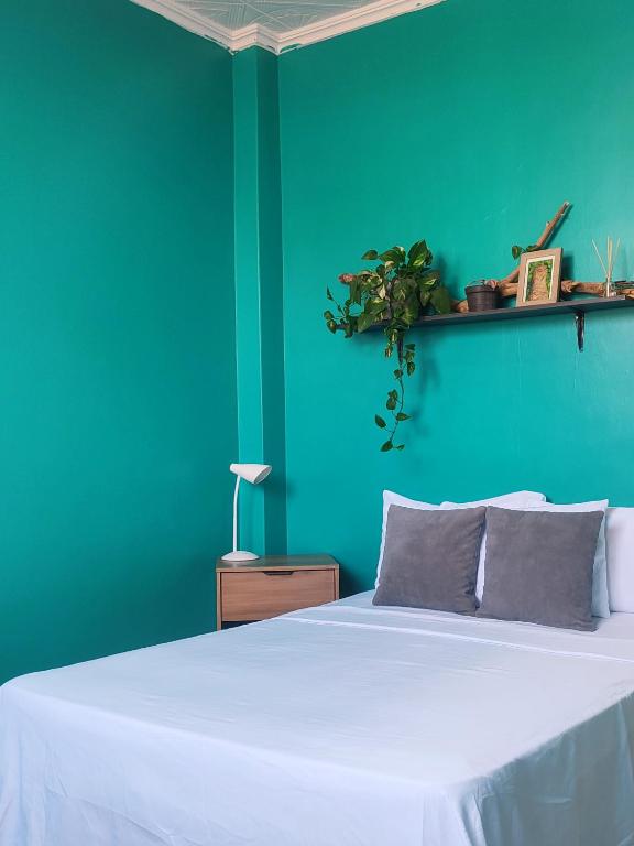 a bedroom with a white bed with a blue wall at Pachamec House in Guayaquil