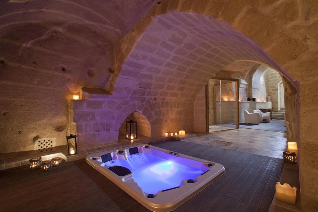 um quarto amplo com uma banheira num edifício de pedra em Antico Convicino Rooms Suites & SPA em Matera