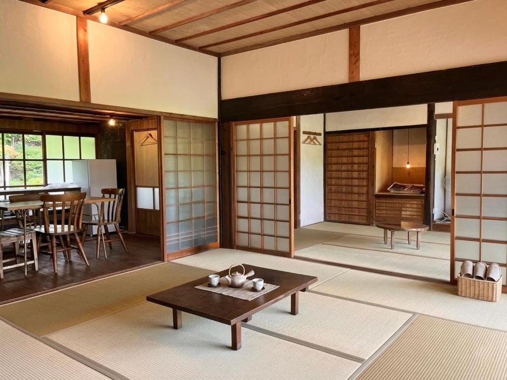 a living room with a table and a dining room at 古民家ステイshinonome inn in Kitsuki