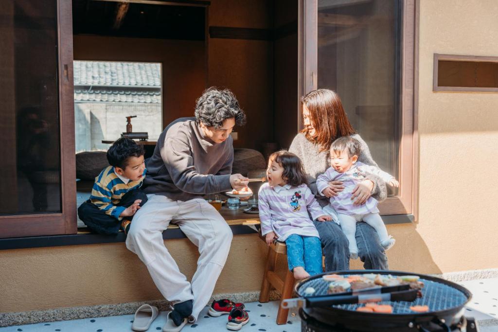 a man and a family sitting in a window eating food at 囲み宿 こわね in Tonosho