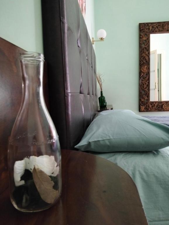 a glass bottle sitting on a table next to a bed at Piazza Verdi Liberty House in Lecce
