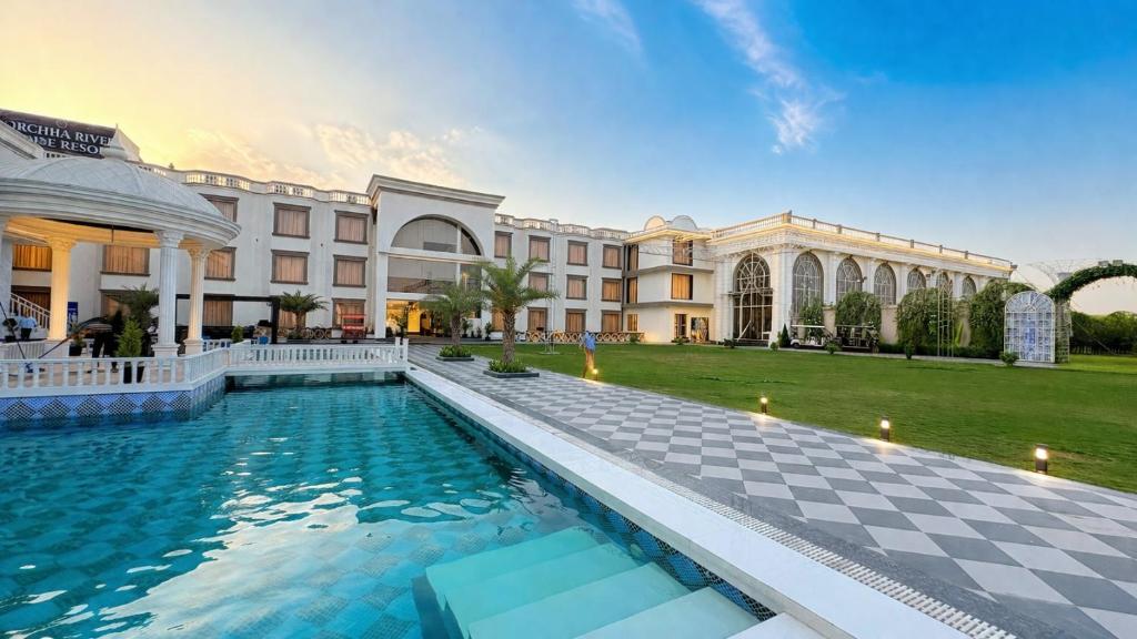 a hotel with a swimming pool in front of a building at Orchha River Stone Resort in Orchha