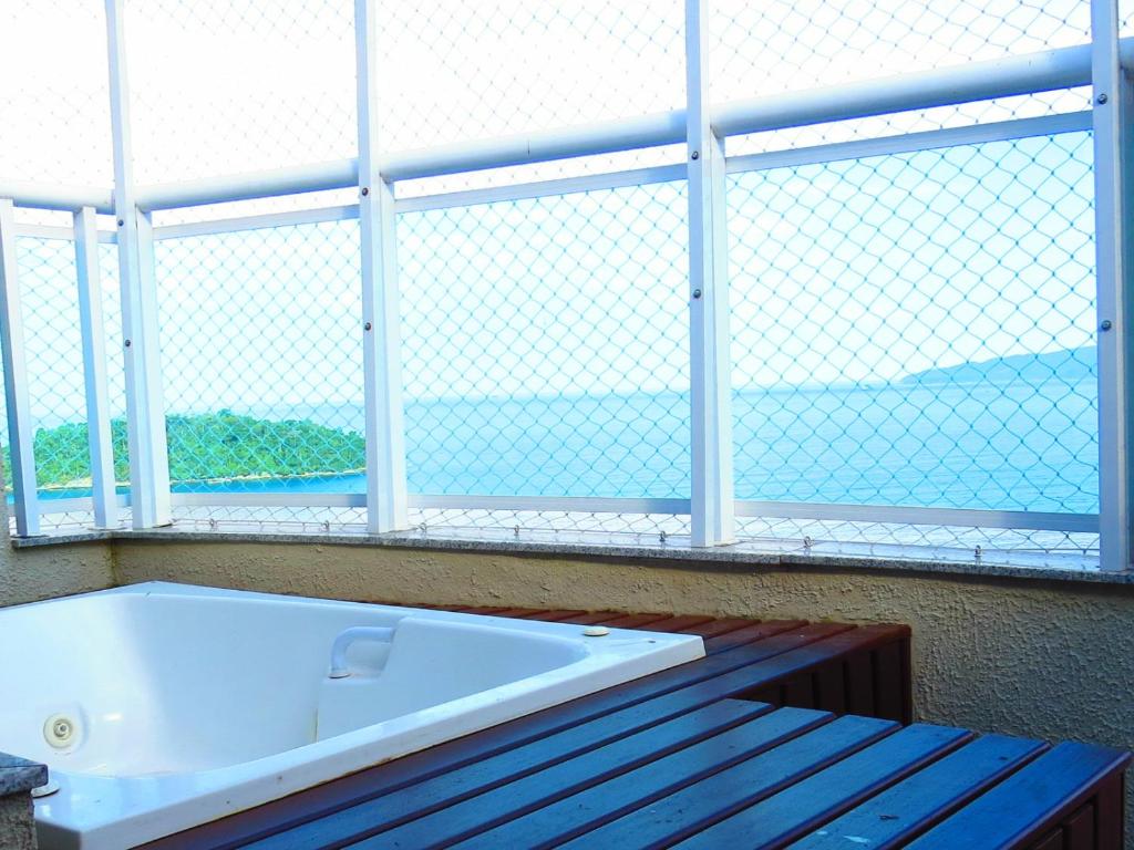 a bath tub sitting in front of a large window at Cobertura Porto Real Suítes - Bloco 5 in Mangaratiba