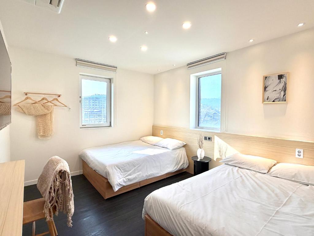 two beds in a room with two windows at Unplug Anguk in Seoul