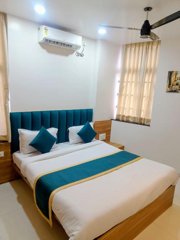 a bedroom with a large bed with blue accents at Hotel Lotus Suites in Miraj