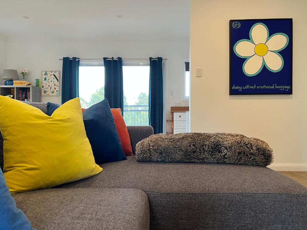 a living room with a couch with yellow and blue pillows at Happy Mountain House in Blackheath