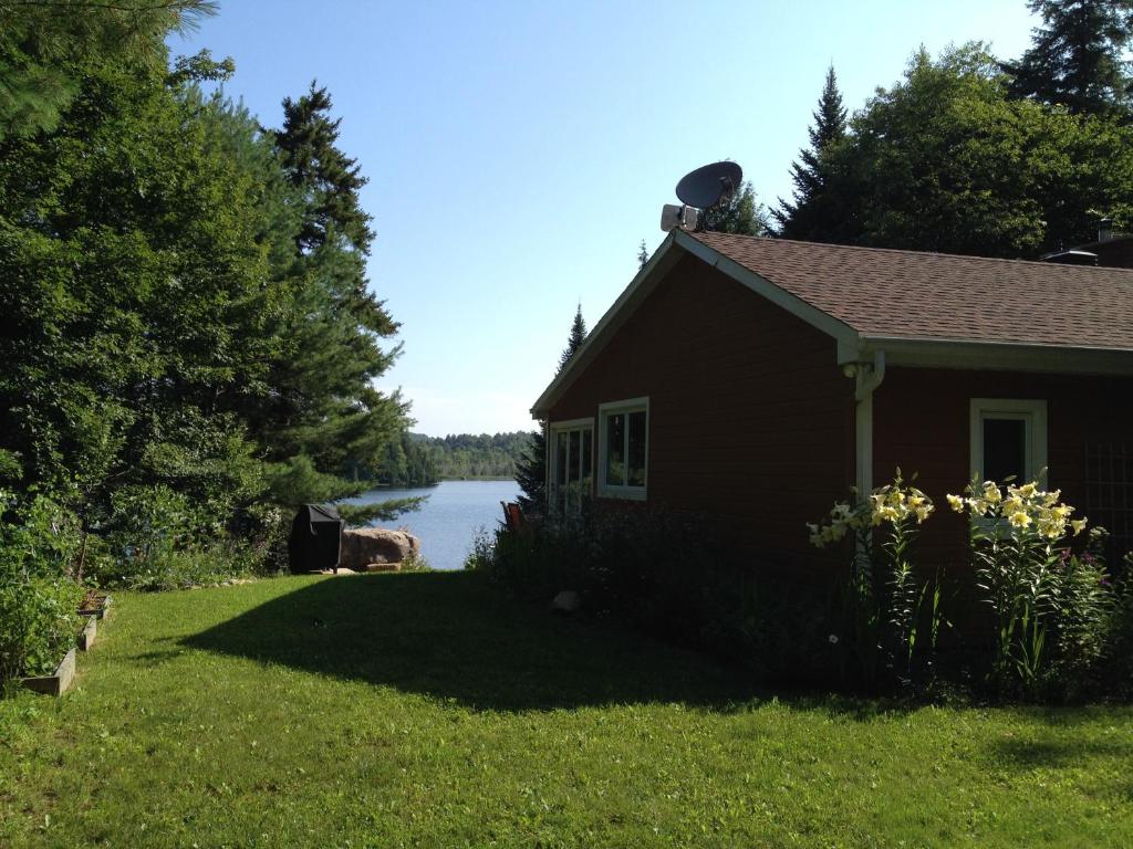 a house in the grass next to a body of water at Lakeside Cottage in Wentworth
