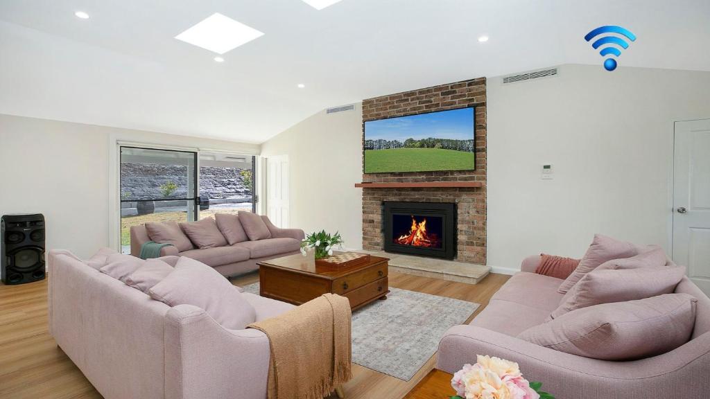 a living room with two couches and a fireplace at Sutton Forest Retreat The Hideaway in Sutton Forest