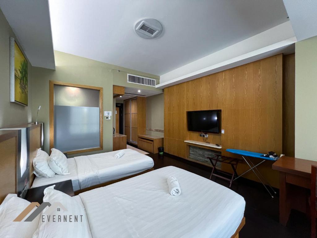 a hotel room with two beds and a flat screen tv at Evernent Meritz in Miri