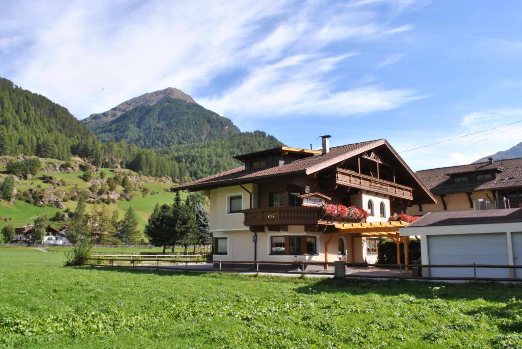 a house in a field with mountains in the background at Apart Tyrolis in Sölden