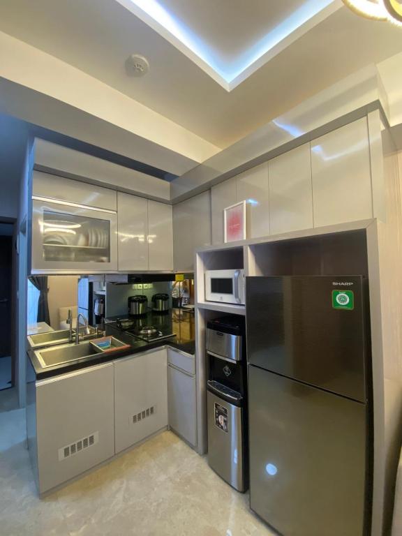 a kitchen with a stainless steel refrigerator and appliances at Podomoro Golf View By Ohara Property in Tjikuda Tiga