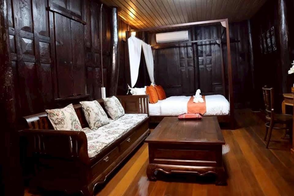 ein Wohnzimmer mit Sofa und Bett in der Unterkunft Doungploy BaanruenThai Homestay in Ban Hua Phrong