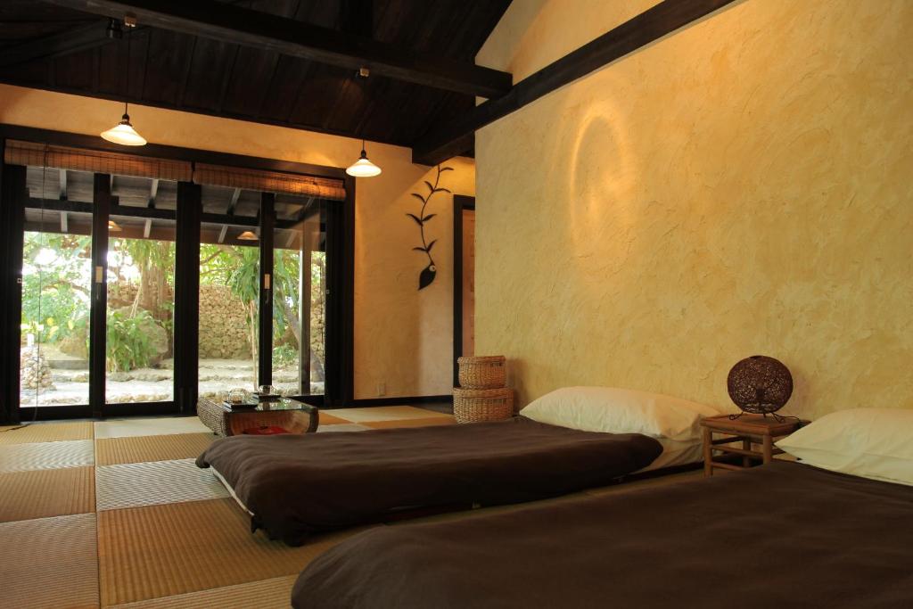 a bedroom with two beds and a large window at Taketomijima Akaneya in Taketomi
