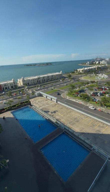 an aerial view of two swimming pools next to the ocean at Delft Apartement in Tanjungbunga