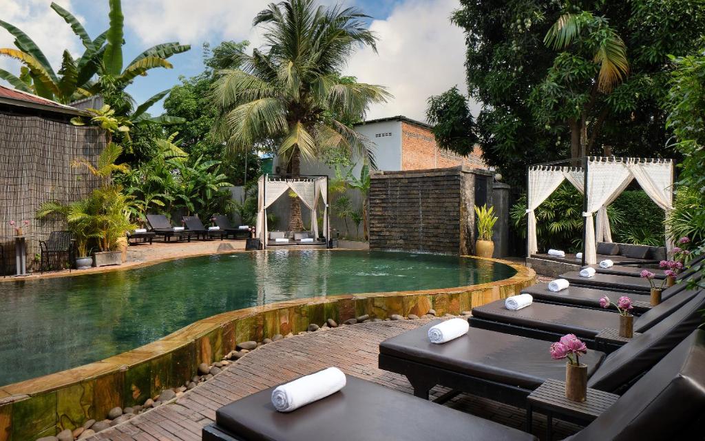 a swimming pool with tables and chairs in a resort at Central Indochine d'Angkor Hotel in Siem Reap